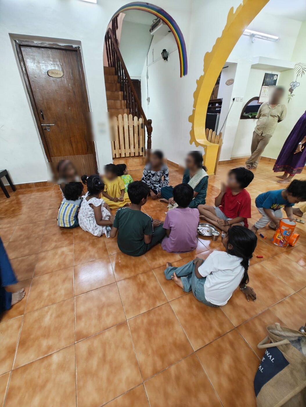 Children sitting together on the floor in a circle, sharing the meal they cooked
