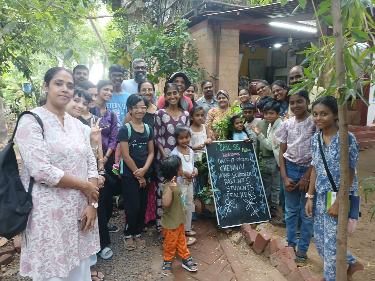 The visiting group outside EPIC-SS, beside a chalkboard reading "EPIC SS Padur welcomes Chennai home schoolers, parents, students, teachers, 17-08-2026"